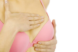 a woman examining her breast for lumps-invasive breast cancer
