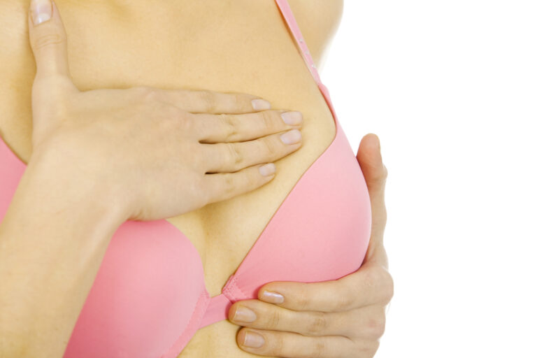 a woman examining her breast for lumps-invasive breast cancer